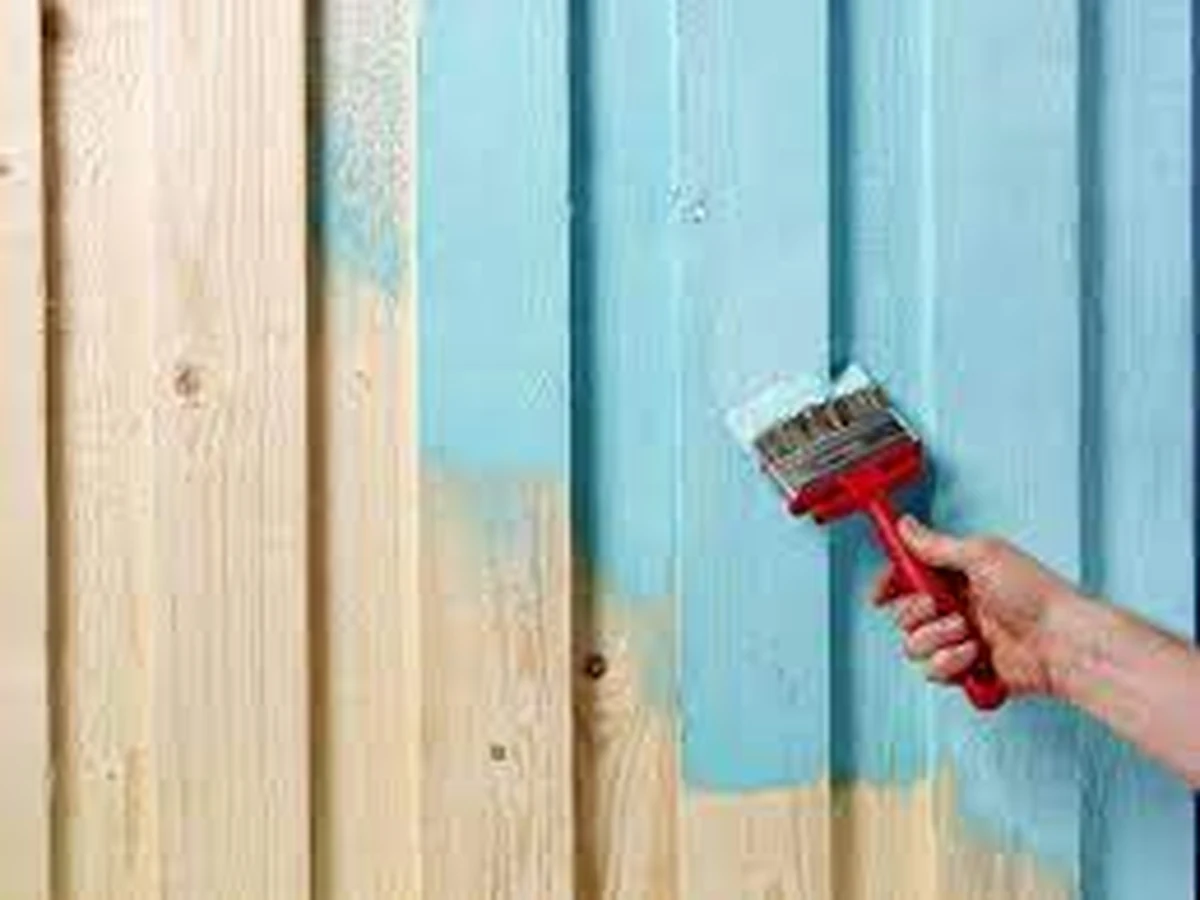 Painter applying paint to a wooden fence — Cambridge Decorators