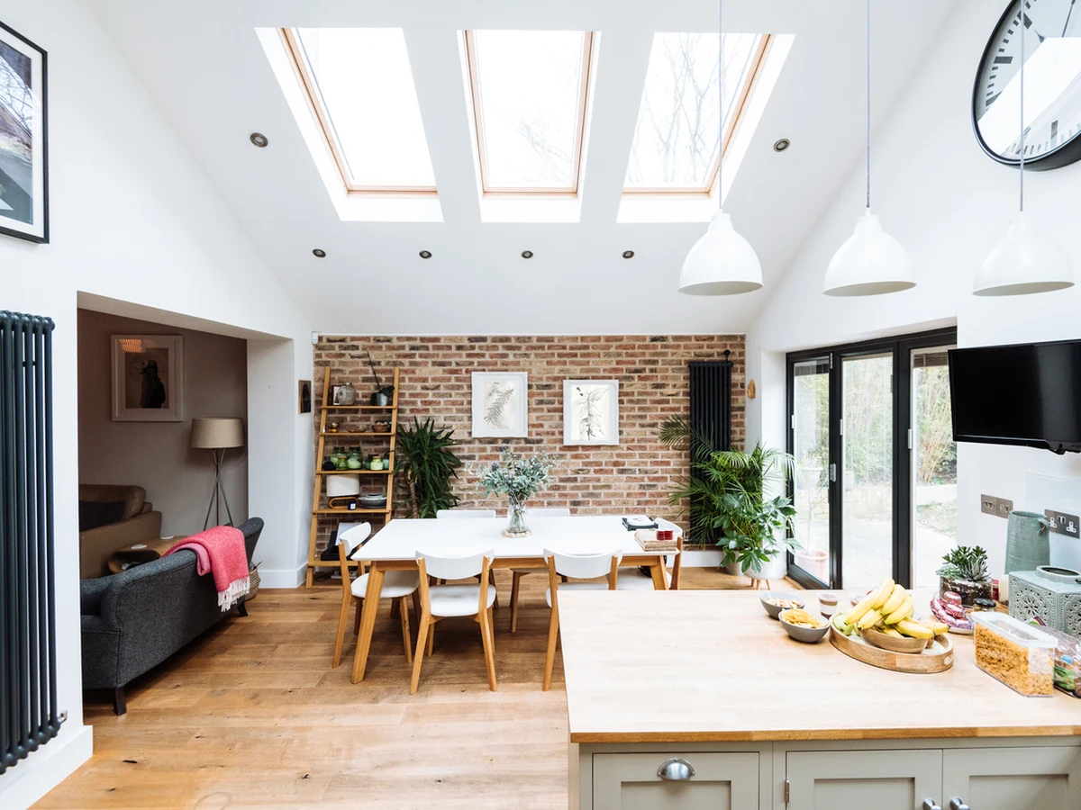 Open-plan kitchen with cream cabinets, a wooden island and skylights