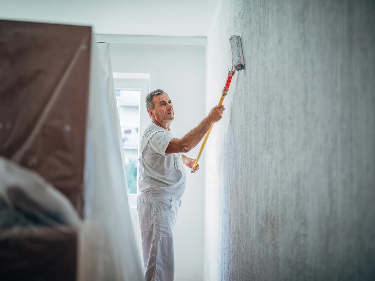 Painter using a roller on interior walls during a Cambridge house repaint