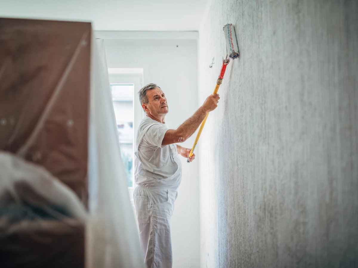Decorator in white overalls preparing surfaces on a Cambridge house painting project