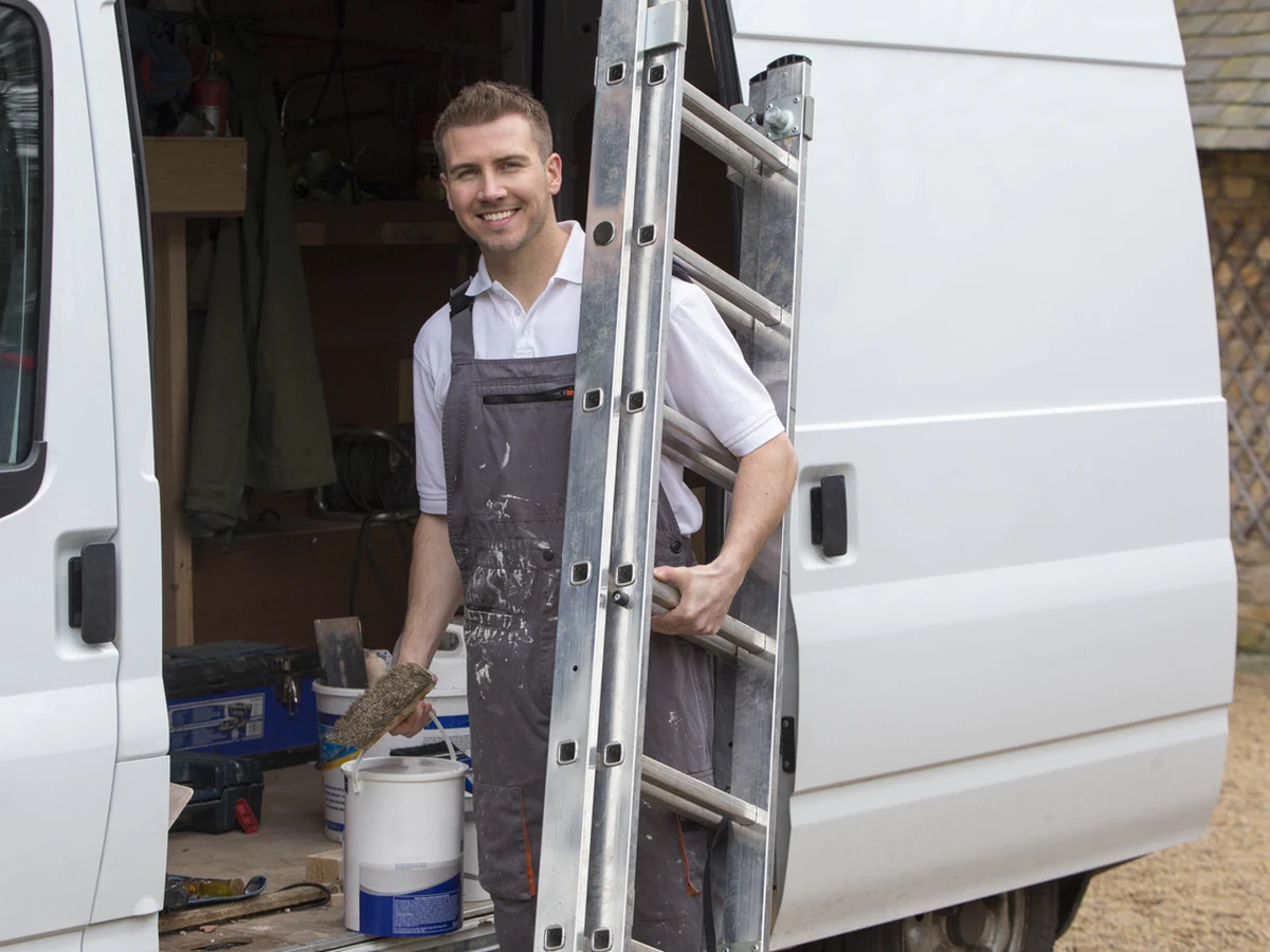 Smiling Cambridge decorator on a ladder during an interior house painting job